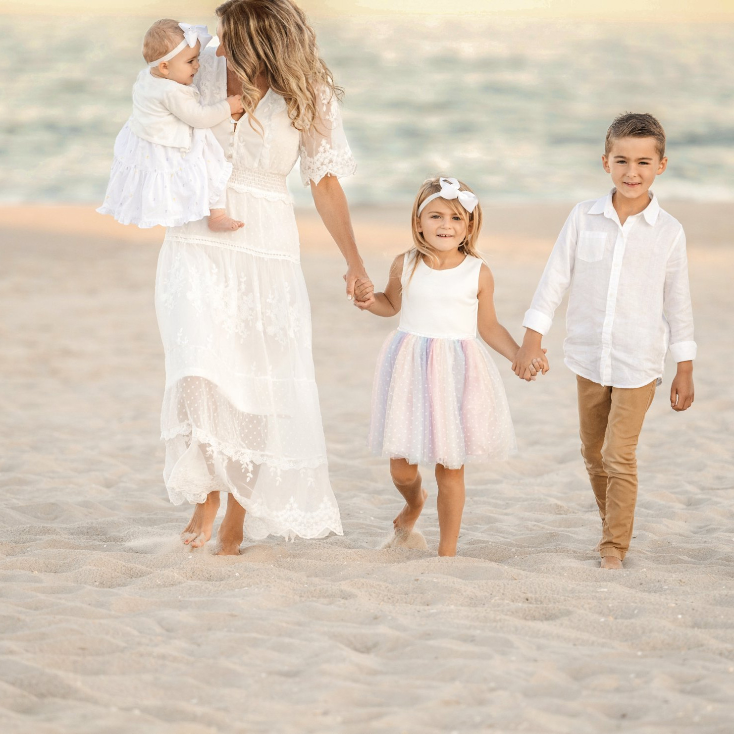 Dr. Kimberly on the beach with her three young children all wearing white.