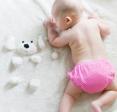 A baby crawling on a soft white blanket.